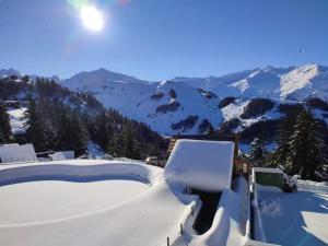 a hot tub covered in snow with mountains in the background at Le Cocon Bleu in Ustou