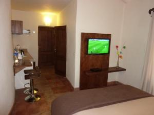Una habitación con TV y una cama en una habitación en Kutty Wasi en Cusco