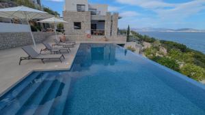 a swimming pool with chairs and a house and the ocean at Villa Levanda in Kiveri