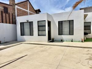 a white house with black shuttered windows at House Ayala 2BR 2Bd in Rosarito