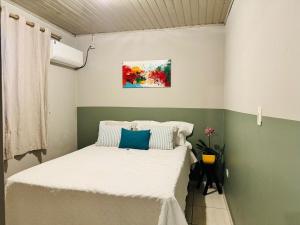 a bedroom with a bed with white sheets and blue pillows at Casa Aconchego 2, Self Check-in in Presidente Prudente