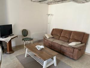 a living room with a brown couch and a table at Au petit soulier de Puisaye in Treigny
