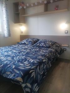 a bed with a blue and white comforter in a room at camping les oyats in Seignosse +40 photos