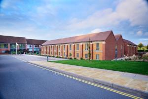 een groot bakstenen gebouw met een weg ervoor bij The Warwickshire Hotel and Country Club in Warwick