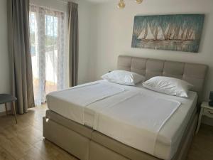 a bedroom with a large bed with white sheets and pillows at Roso Seafront House in Selca kod Bogomolja