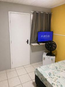 a bedroom with a bed and a tv on a shelf at Quarto em Matinhos | Viva o Melhor do Litoral in Matinhos