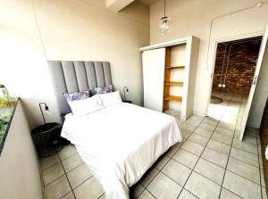 a bedroom with a white bed in a room at Tulisa Park in Johannesburg +4 photos