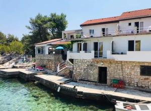 a house on the water next to a dock at Roso Seafront House in Selca kod Bogomolja