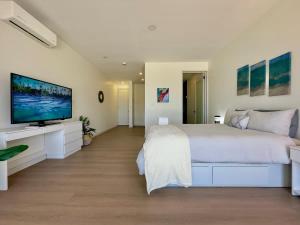 a white bedroom with a large bed and a flat screen tv at Little Pearl Sea View Studio in San Antonio del Mar