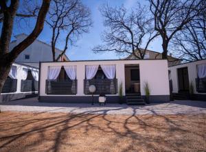 a white house with black shutters and a tree at Lux Mobile Homes Vodice in Vodice