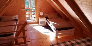 a attic room with two beds and a window at Domek Pod Sosnami in Kuźnica Nowa