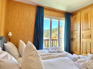 two beds in a room with a window at Chalet Le Nid D'argent - Dans la nature in Crans-Montana