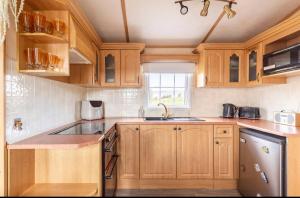 a kitchen with wooden cabinets and a sink at Attymchugh Lodge in Corlee