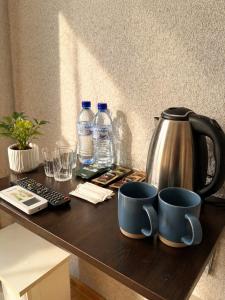 a table with two coffee mugs and water bottles at Salo Pool Hotel by the Sea in Gonio +4 photos