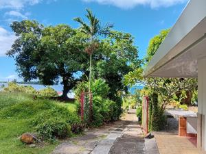 a walkway to a house with a tree in the background at Hiro'a - Fare Orotia in Taputapuapea