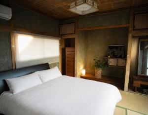 a bedroom with a white bed and a window at 宇佐神宮近く- 神さまと仏さまと kamisama to hotokesama to in Nagasu
