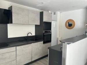 a kitchen with white and black cabinets and a sink at L'échappée Méditerrannée in Vallauris