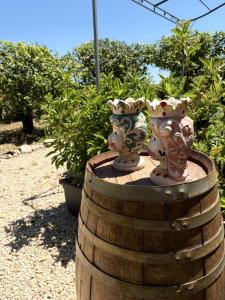 two vases sitting on top of a wooden barrel at Green House La Torre in Avola
