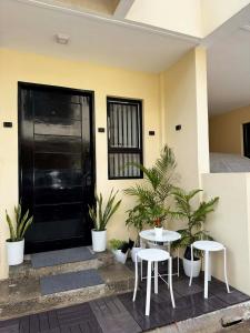 a building with a black door and two tables and plants at Entire House with Parking, Full Kitchen and Near SRP, Seaside and Nustar in Talisay