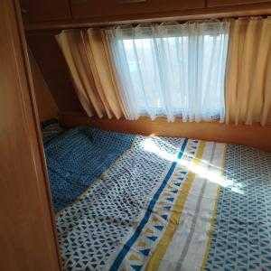 a small bed in a room with a window at Caravane in Port-sur-Saône