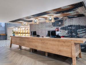 a woman standing at a counter in a restaurant at Ibis Riyadh Hotel Al Muhammadiyah United Company Branch in Riyadh