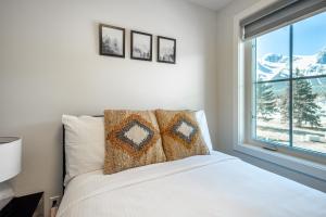 a bedroom with a white bed and a window at Golden Ridge Collection in Canmore +37 photos