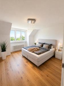 a white bedroom with a large bed and wooden floors at Stylish house with garden, sauna & pool in Mörschwil +9 photos