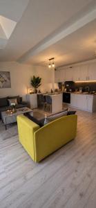 a living room with a yellow couch and a kitchen at Mountain View Apartament Termy Chochołowskie 5 min in Suchá Hora
