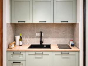 a kitchen counter with a sink and white cabinets at Lungolago Apartment Ohrid in Ohrid