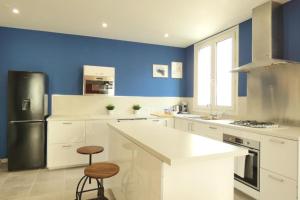 a kitchen with white cabinets and a blue wall at Lambraz in Brest