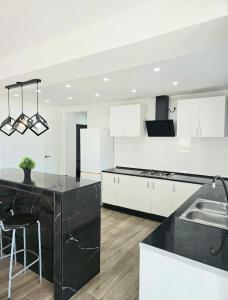 a kitchen with white cabinets and a black counter top at Villa Los Naranjos in Carcaixent +4 photos