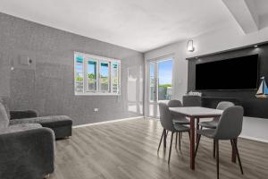 a living room with a table and chairs and a tv at Balandras Beach Stay 1 Beach & Pool Access in Dorado +31 photos