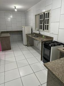 a kitchen with white tile floors and a stove and refrigerator at Kairos Pousada e Hostel in Cabo de Santo Agostinho