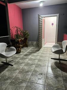 a room with two white chairs and a pink wall at Kairos Pousada e Hostel in Cabo de Santo Agostinho +1 photo