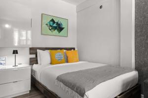 a white bedroom with a bed with colorful pillows at Balandras Beach Stay 3 Beach & Pool Access in Dorado