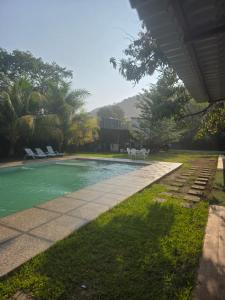 a swimming pool in a backyard with chairs and trees at Harvestmoon Boutique Hotel in Las Piedras