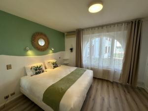 a bedroom with a large bed and a large window at Hotel Chiffre in Albi