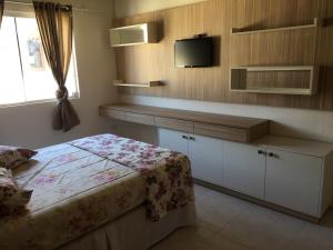 Un dormitorio con una cama y un televisor en la pared. en Apto 103 Maria Helena, en Torres