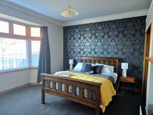 a bedroom with a large bed with a yellow blanket at Cosy On Till in Oamaru