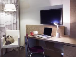 ein Zimmer mit einem Schreibtisch mit einem Laptop und einer Lampe in der Unterkunft Ibis Styles Roma Eur in Rom