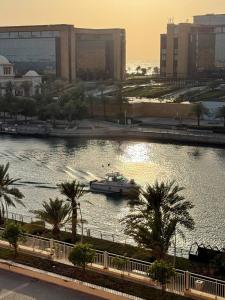 a boat in a river with palm trees and buildings at شاطئ المرجان in King Abdullah Economic City