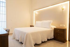 a bedroom with a white bed with a large headboard at Rural VillaReyes in Cabeza la Vaca