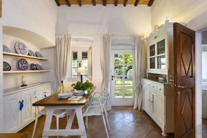 a kitchen with white cabinets and a table and chairs at Porto Cervo Sea and Nature Villa in Porto Cervo