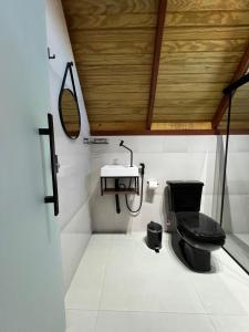 a bathroom with a black toilet and a sink at Chalés Pôr do Sol in Mucugê +14 photos