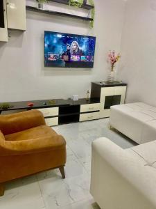 a living room with a couch and a tv on the wall at CHAMBREs SALON MEUBLÉ HD in Yamoussoukro