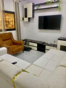 a living room with a tv and a couch and a chair at CHAMBREs SALON MEUBLÉ HD in Yamoussoukro