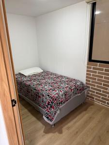a small bed in a small room with a bedspread at Boreal House in Manizales