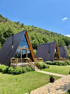 a house with a gambrel roof and a deck at Alpine Cabins Gjinar in Gjinar