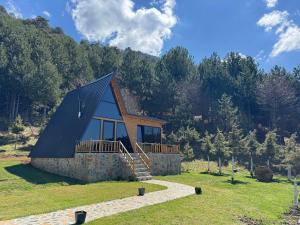a small cabin in the middle of a field with trees at Alpine Cabins Gjinar in Gjinar