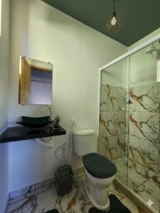 a bathroom with a toilet and a glass shower at Morada Iluminada Aconchego com Ar condicionado e Lareira in Miguel Pereira +8 photos
